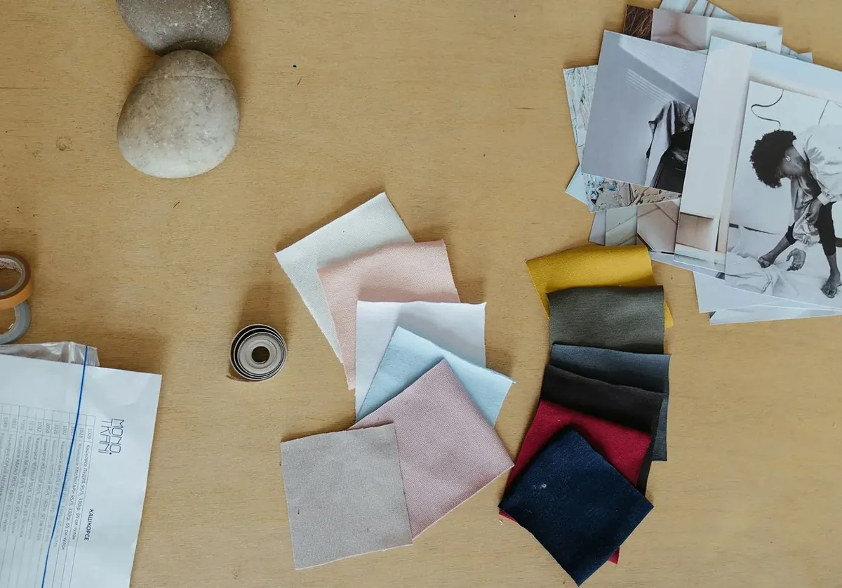 Fabric swatches in pink, olive, navy and charcoal beside magazine clippings and a pebble
