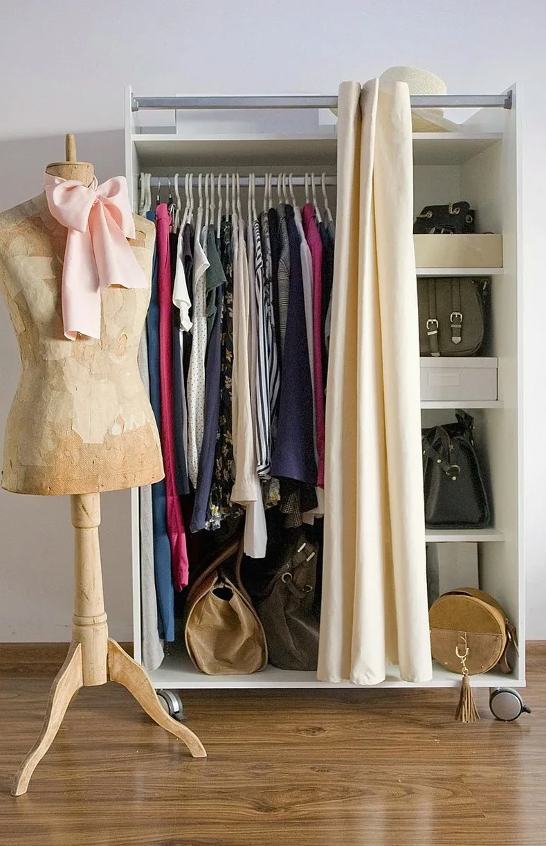 Clothes rail with hanging garments, handbags on shelves and a wooden dress form