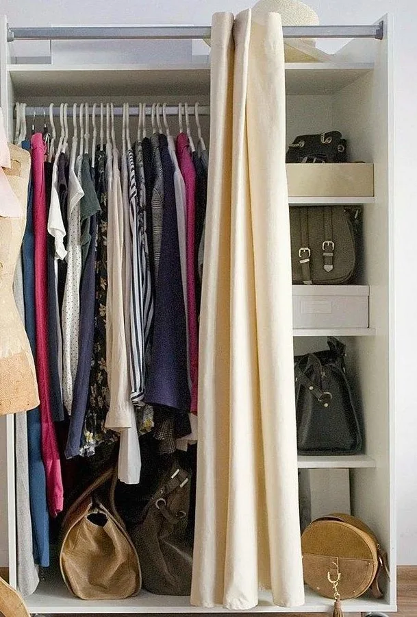 Garments hanging on a neutral clothes rail beside a cream curtain