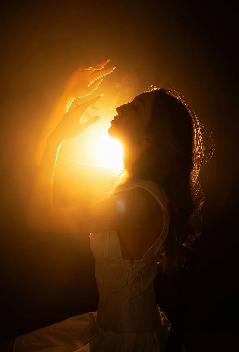 Woman in profile lit from behind by warm sunlight